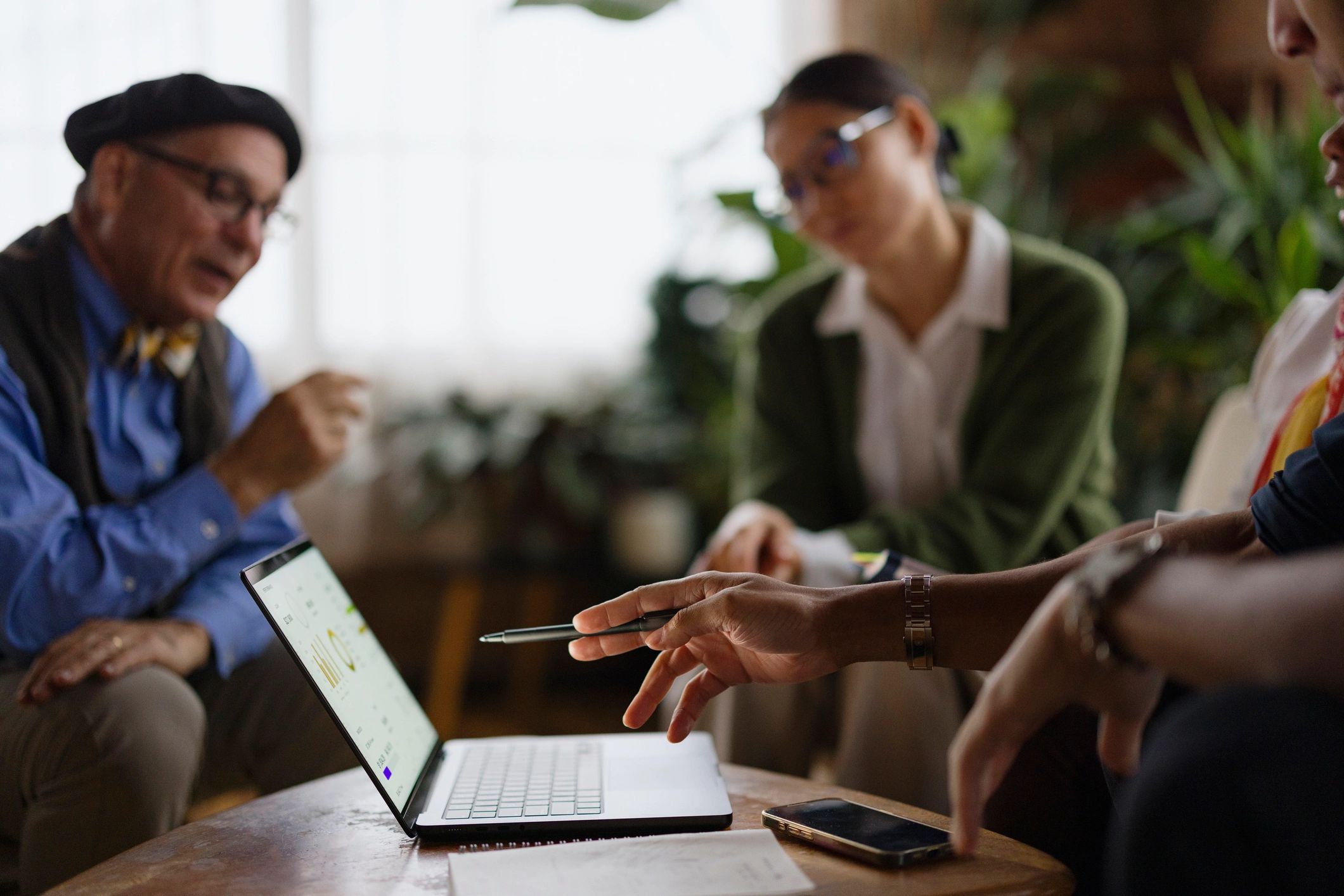 Business colleagues collaborating while reviewing charts on a laptop